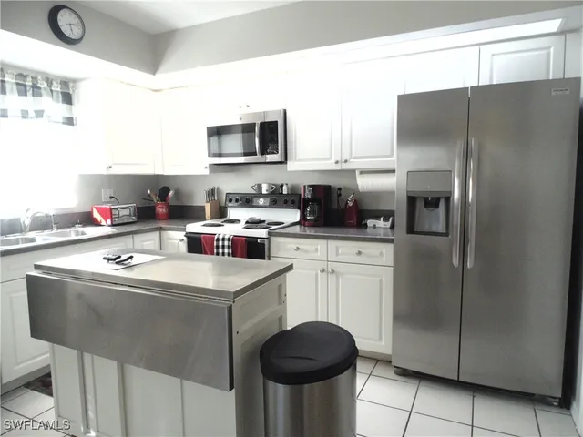 a kitchen with stainless steel appliances granite countertop a sink stove refrigerator and cabinets