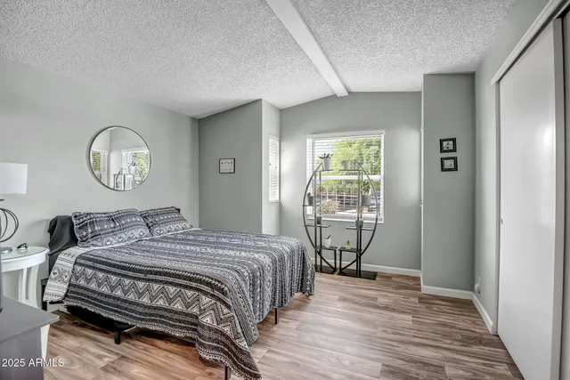 a bedroom with a bed a mirror on the dresser and a window