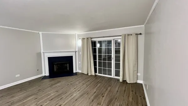 an empty room with wooden floor a fireplace and windows