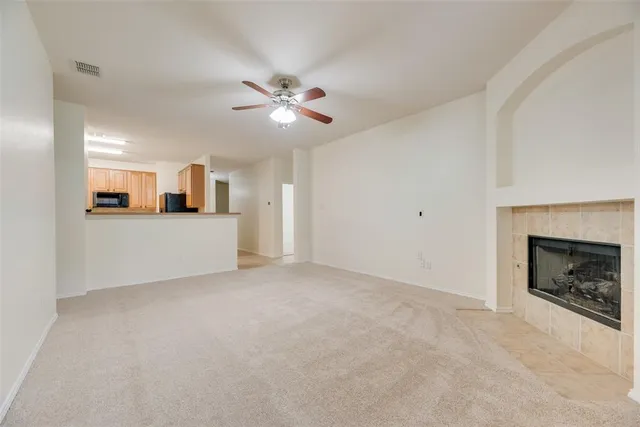 a view of a room a ceiling fan a fireplace and entryway