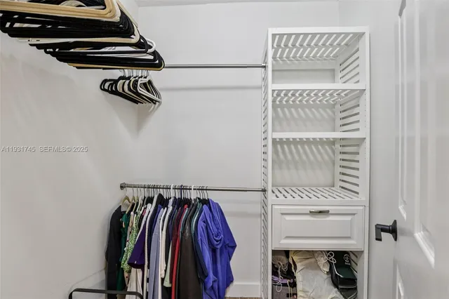 a view of walk in closet with clothes and shoes