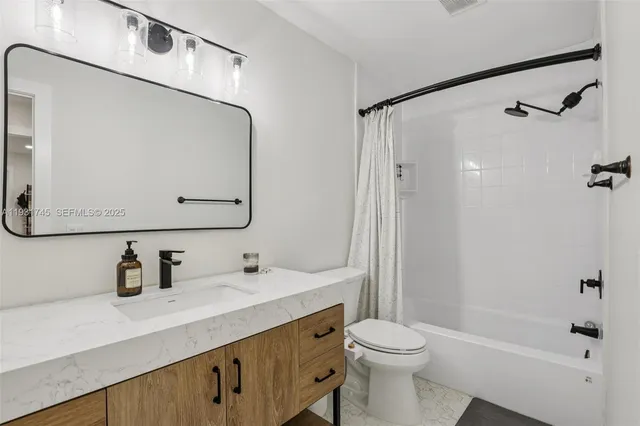 a bathroom with a sink a toilet and shower a mirror