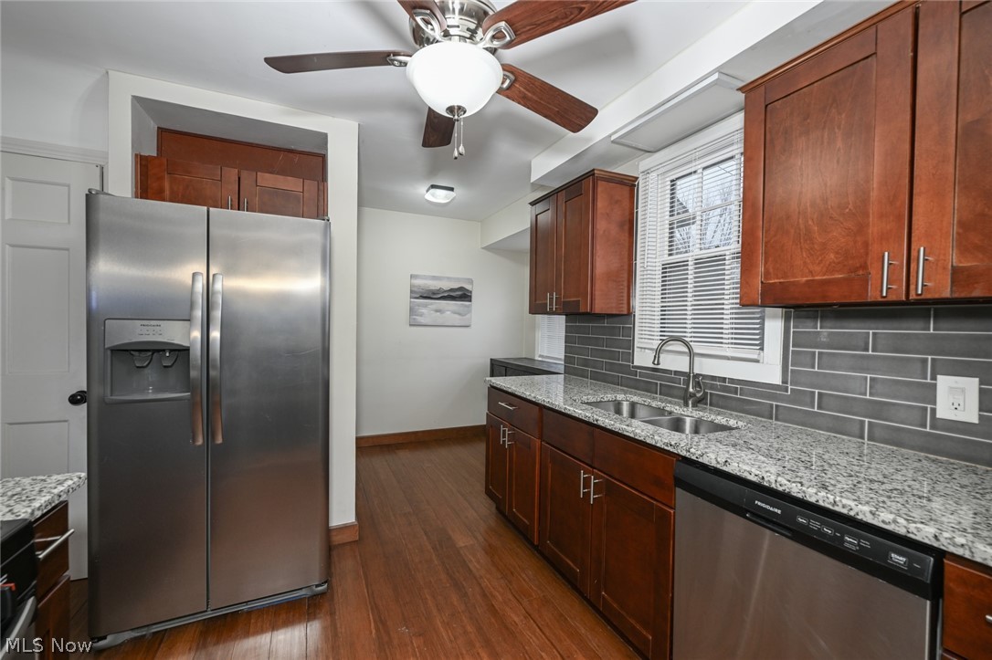 3699 Bainbridge Road Cleveland Heights, OH 44118 - Photo 12 of 37 Kitchen featuring wood-finish flooring, cherry-toned cabinetry, granite countertops, a subway tile backsplash, and stainless steel appliances