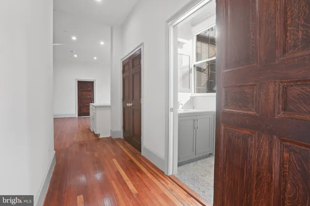 a view of a hallway with wooden floor and a bathroom