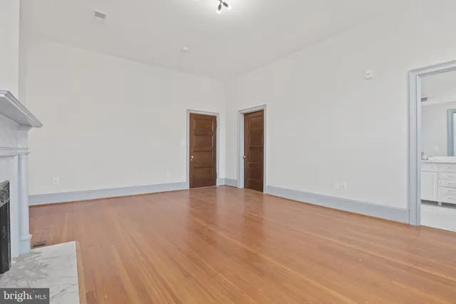 a view of an empty room with wooden floor and a fireplace