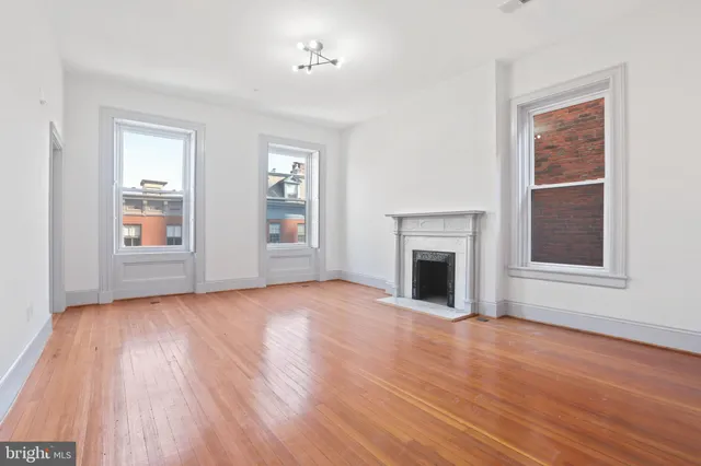 wooden floor fireplace and windows in an empty room