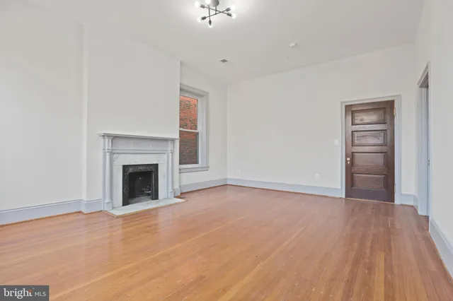 a view of empty room with wooden floor and fireplace