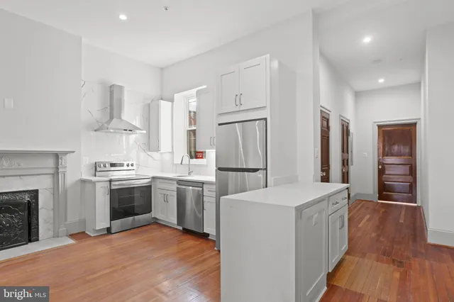 a kitchen with stainless steel appliances granite countertop a stove top oven a sink dishwasher and a refrigerator with wooden floor