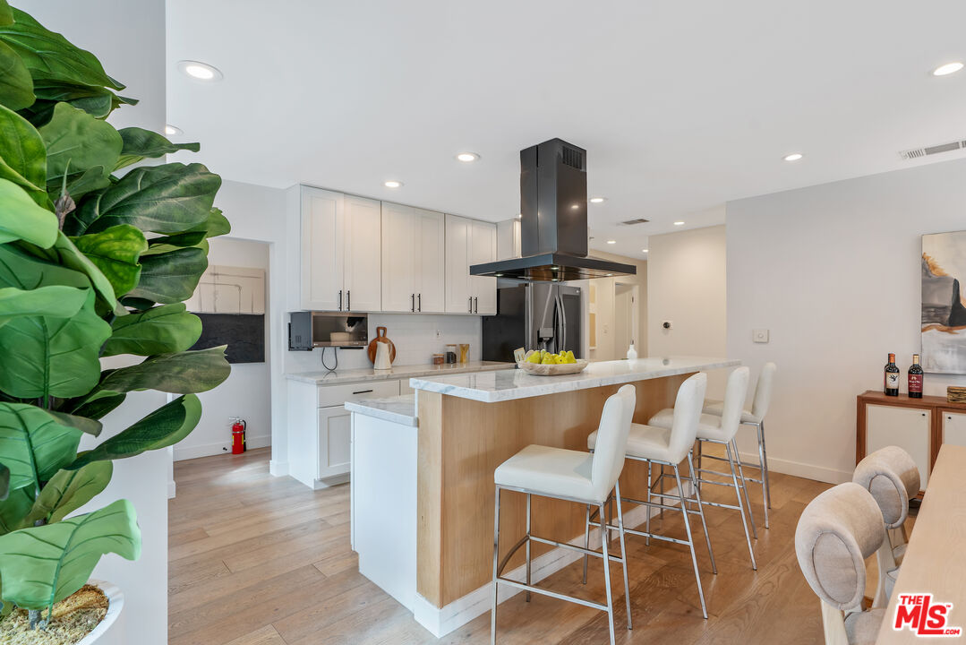 1645 South Sierra Bonita Avenue Los Angeles, CA 90019 - Photo 16 of 62 a kitchen with white cabinets and chairs