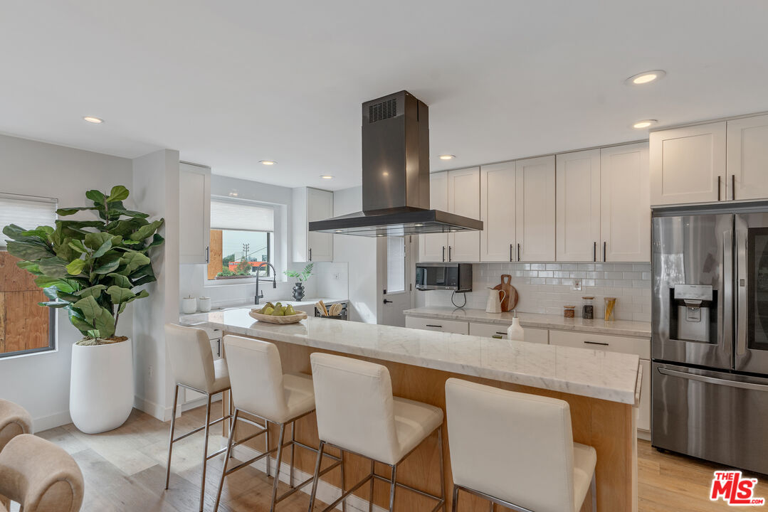 1645 South Sierra Bonita Avenue Los Angeles, CA 90019 - Photo 19 of 62 a kitchen with granite countertop a counter space cabinets stainless steel appliances and a potted plant