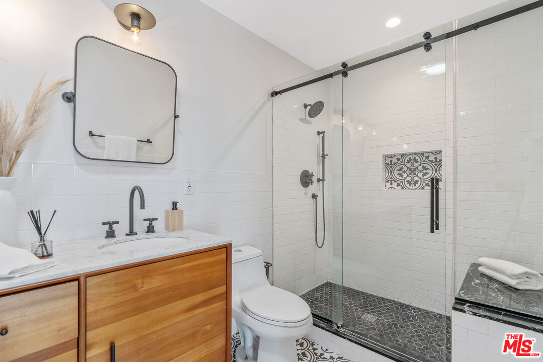 1645 South Sierra Bonita Avenue Los Angeles, CA 90019 - Photo 37 of 62 a bathroom with a granite countertop sink mirror vanity and toilet