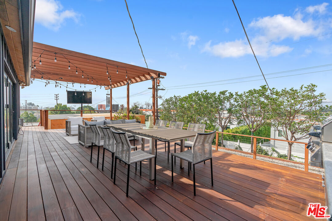 1645 South Sierra Bonita Avenue Los Angeles, CA 90019 - Photo 50 of 62 a view of a patio with table and chairs under an umbrella with wooden floor