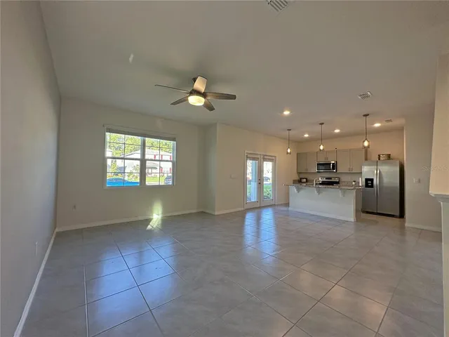 a view of an empty room and a kitchen with a sink