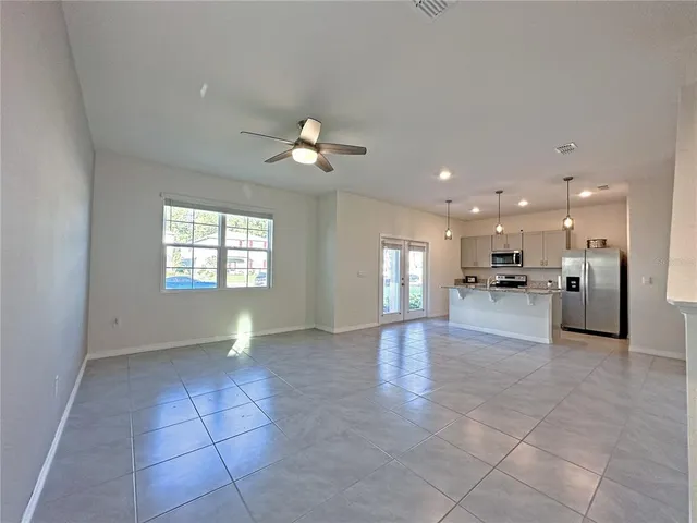 a view of an empty room and a kitchen
