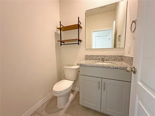 a bathroom with a granite countertop toilet sink and mirror