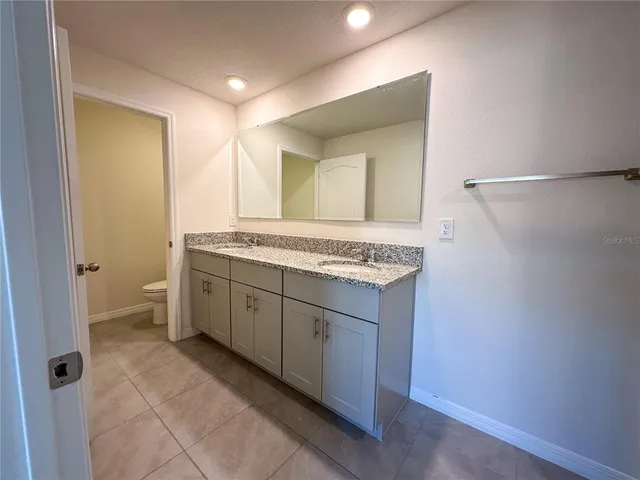 a spacious bathroom with a granite countertop sink and a mirror
