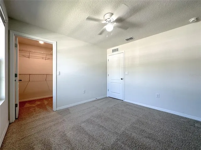 an empty room with closet and a chandelier fan