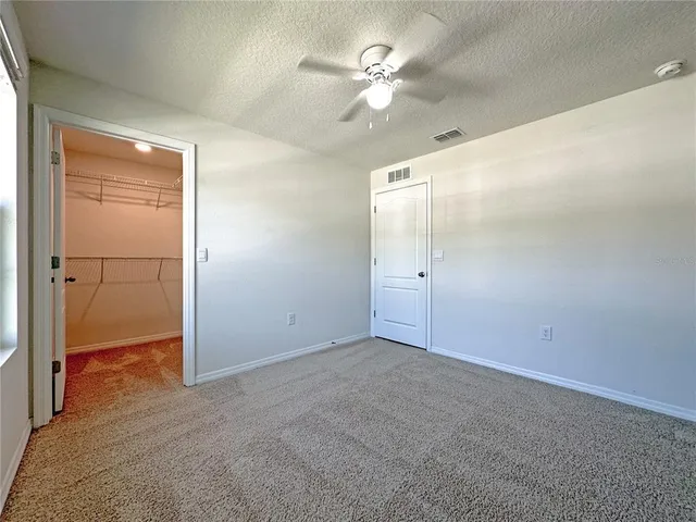 an empty room with closet and a chandelier fan