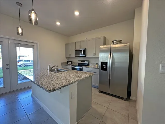 a kitchen with stainless steel appliances granite countertop a table a refrigerator and a sink