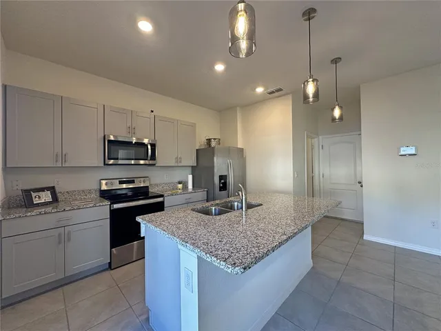 a kitchen with kitchen island granite countertop stainless steel appliances a sink stove and refrigerator
