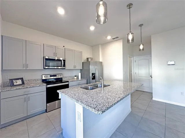 a kitchen with kitchen island granite countertop stainless steel appliances a sink stove and refrigerator