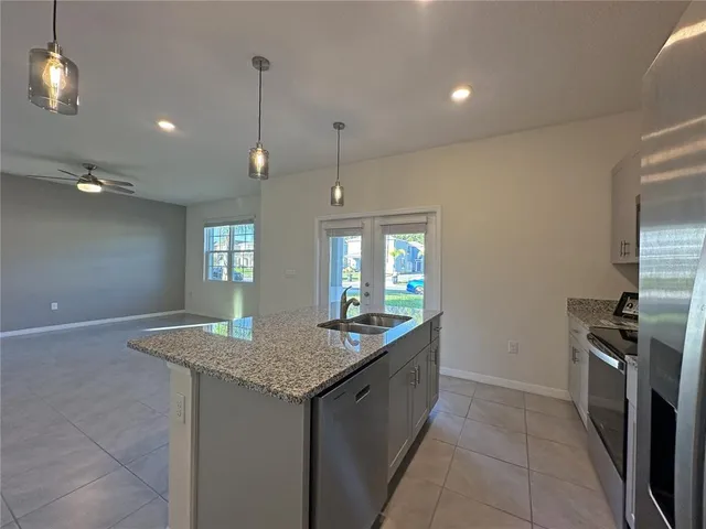 a kitchen with granite countertop kitchen island a sink stainless steel appliances and a window