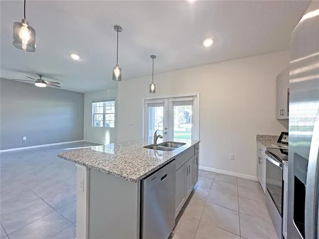 a kitchen with granite countertop kitchen island a sink stainless steel appliances and a chandelier