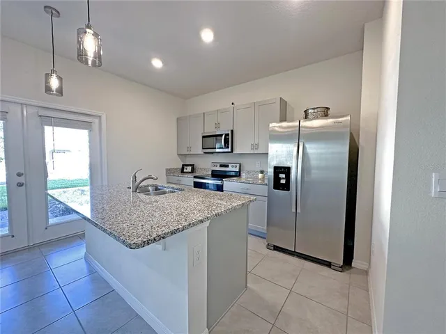 a kitchen with stainless steel appliances granite countertop a stove a refrigerator a sink a microwave and island