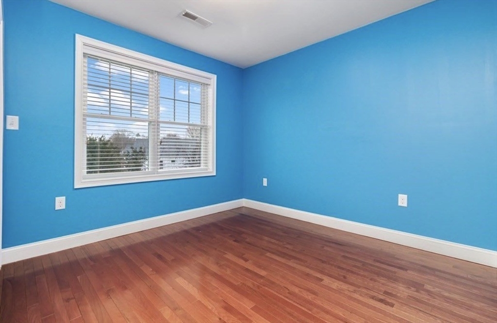 38 Webster Street, Unit 2 Needham, MA 02494 - Photo 13 of 16 an empty room with wooden floor and windows