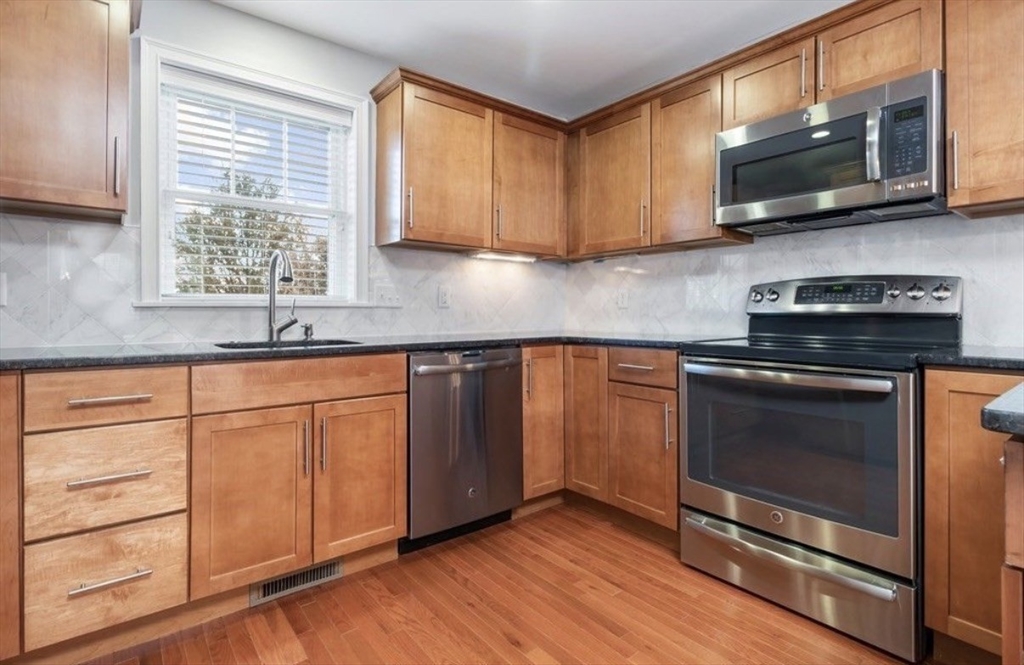 38 Webster Street, Unit 2 Needham, MA 02494 - Photo 5 of 16 a kitchen with granite countertop wooden cabinets stainless steel appliances and a window