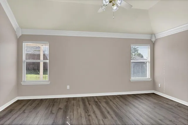 an empty room with wooden floor and windows
