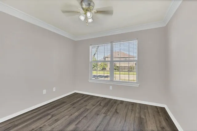 an empty room with wooden floor chandelier fan and windows