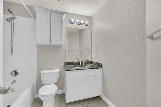 a bathroom with a granite countertop toilet a sink and a mirror