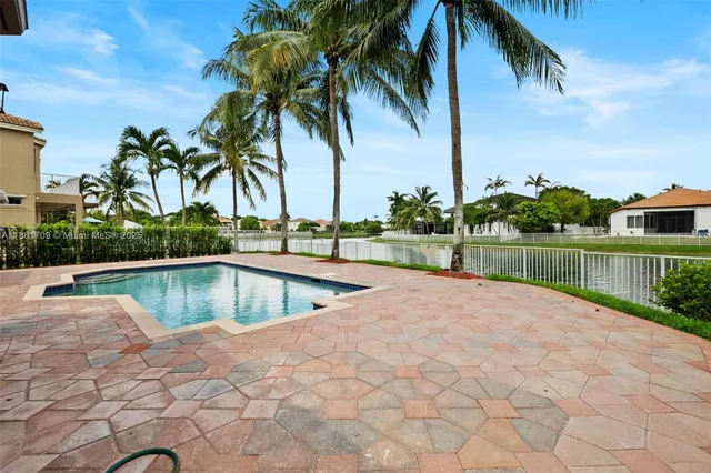 a view of swimming pool with a yard and palm trees
