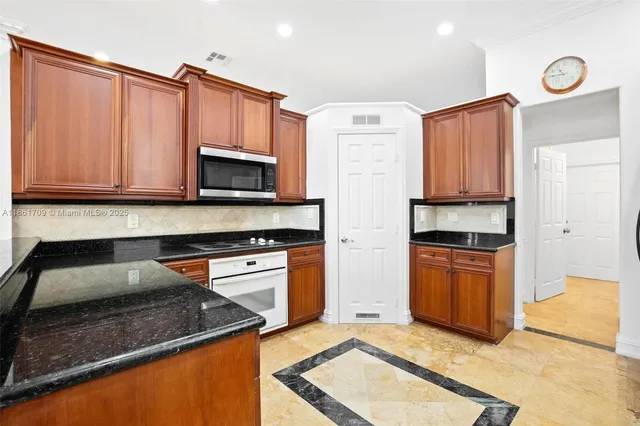 a kitchen with granite countertop a refrigerator stove and microwave
