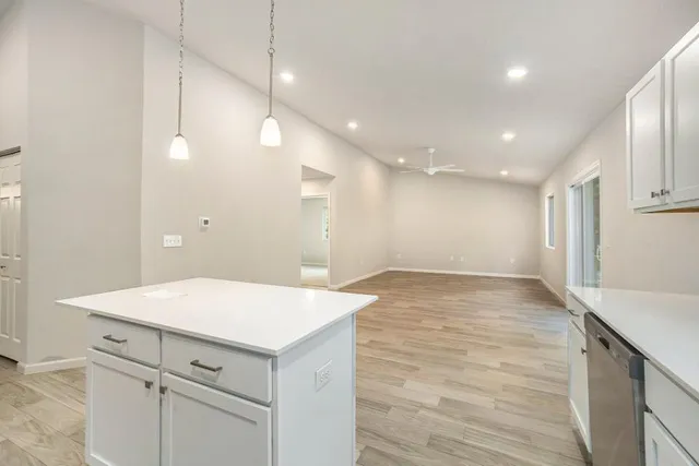 a view of a kitchen island a sink and dishwasher with wooden floor
