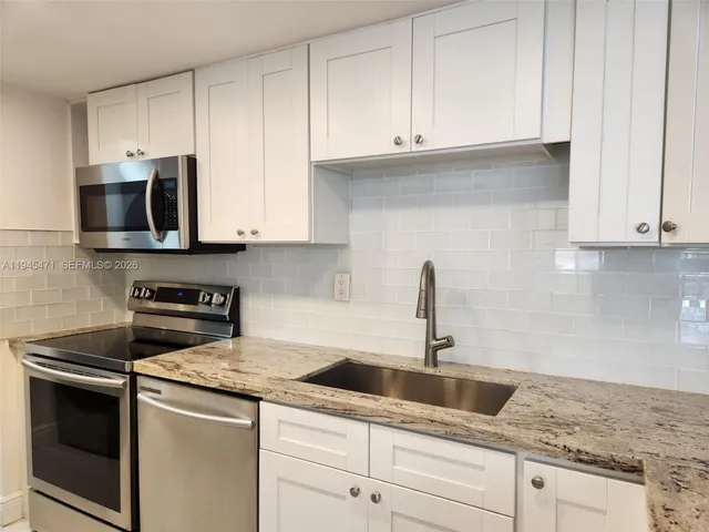 a kitchen with granite countertop white cabinets and a sink