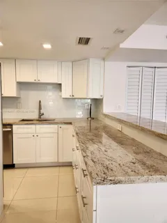 a kitchen with granite countertop a sink a stove top oven a counter space and cabinets
