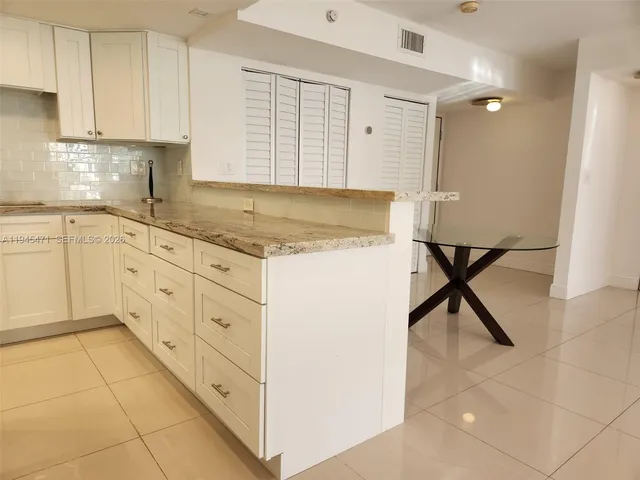 a kitchen with granite countertop white cabinets and white appliances