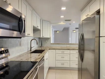 a kitchen with granite countertop a refrigerator and a sink
