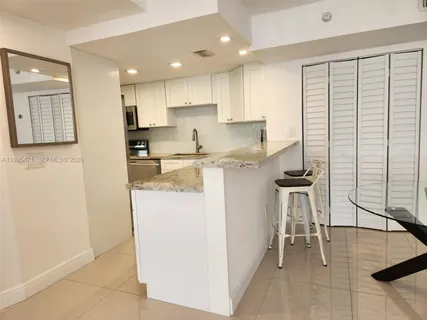 a kitchen with a sink a refrigerator and chairs