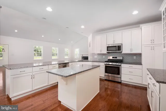 a kitchen with granite countertop a stove a sink and a refrigerator
