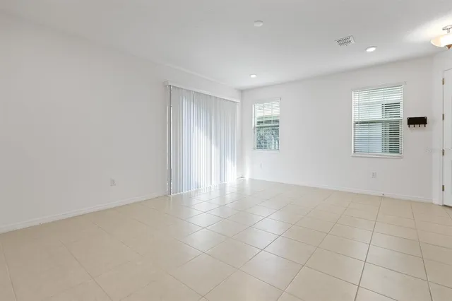 a view of an empty room with wooden floor and a kitchen