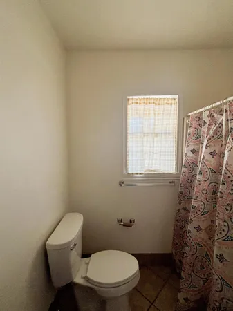 a white toilet sitting next to a window in a bathroom