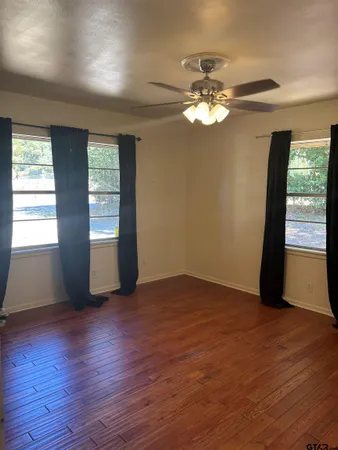 a view of an empty room with a window and wooden floor