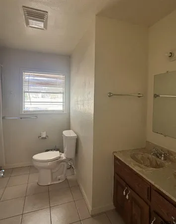 a bathroom with a granite countertop sink a toilet and a mirror