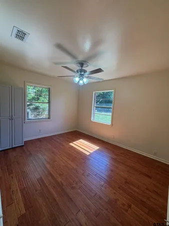 an empty room with wooden floor chandelier and windows