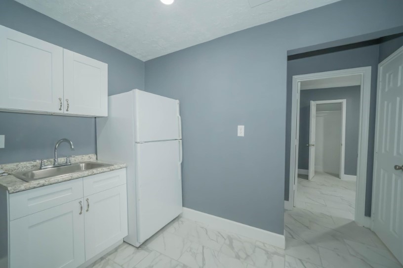 1426 Telephone Road Houston, TX 77023 - Photo 6 of 10 a kitchen with a sink a refrigerator and cabinets