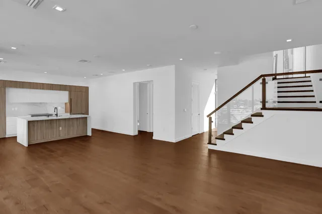 a view of an empty room with window and wooden floor