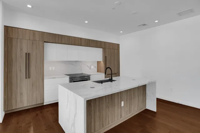 a view of kitchen with granite countertop window sink and cabinets